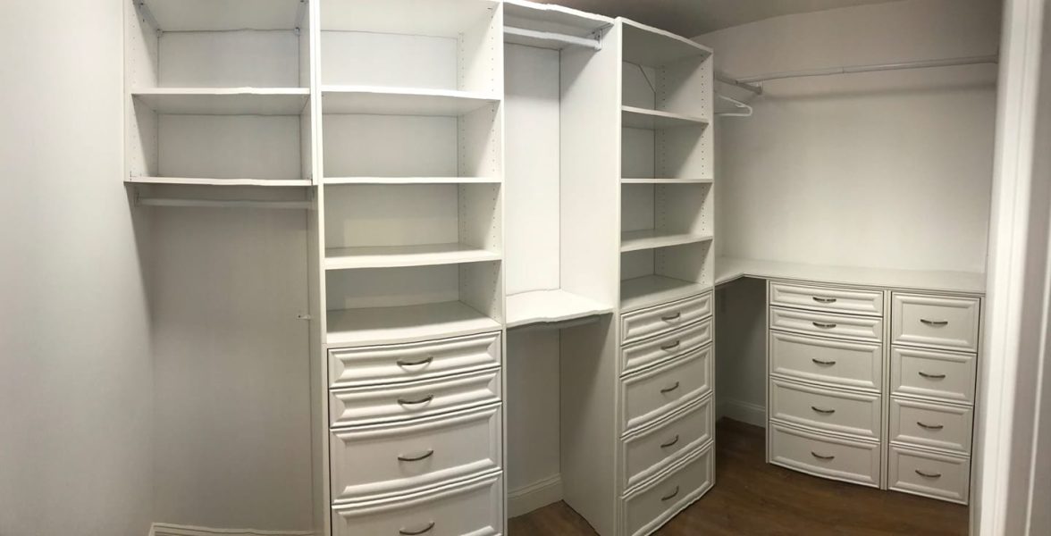 A custom built-in closet with organized shelves, drawers and polished hardware