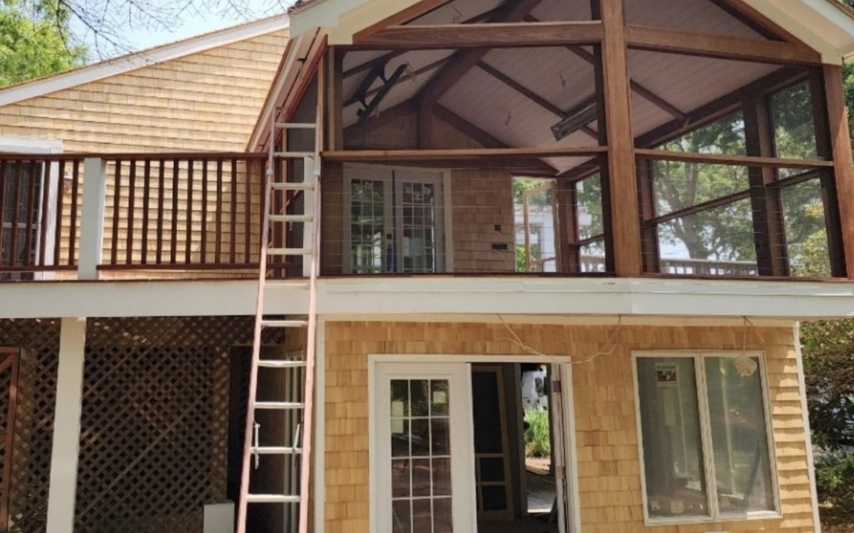 A two-story home addition under construction with a screened gable end