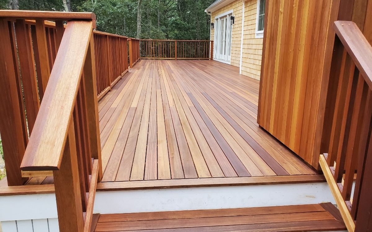 A mahogany deck with matching rail and stairs alongside a shingled house