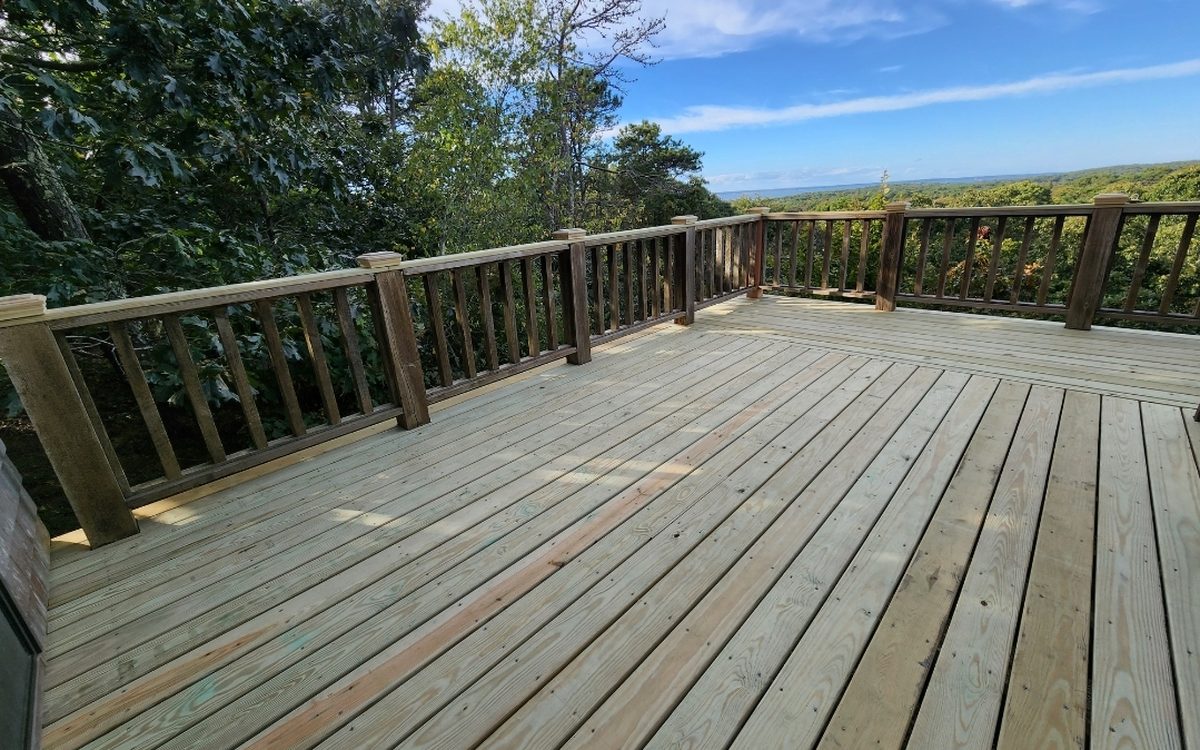 A new pressure-treated deck and railing set against the treeline