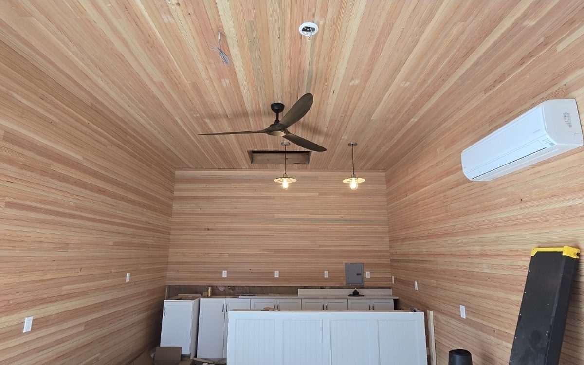 A room lined floor to ceiling in clear cedar with a fan and pendant lights