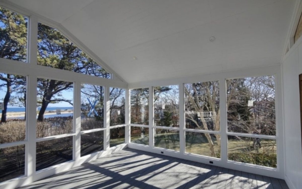 A bright white screened porch looking out toward the water